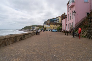 Cromer, UK- 18 Mayıs 2025: Pembe ve Sarı Evli Renkli Sahil Kenarı Gezisi, İngiliz Sahil Köyü Yürüyüşü ve Bulutlu Gökyüzü Sahil Manzarası