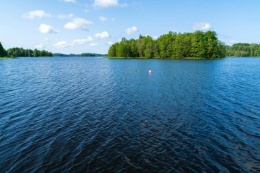 Yeşil Orman Adası ve Açık Su ile Güzel Mavi Göl Bir Yaz Günü. Ağaçlar, Gökyüzü, Bulutlar ve Huzurlu Su Yüzeyi Görünümü ile Doğal Manzara.