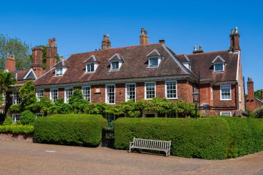 Norwich, UK- 17 Mayıs 2025: Yurt pencereli ve açık mavi gökyüzü altında manikürlü çitleri olan tarihi Gürcü tuğla köşkü. Birden fazla bacası olan geleneksel İngiliz kırsal mimarisi 