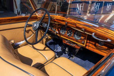 Norwich, UK- 17 Mayıs 2025: Cilalanmış ahşap gösterge paneli ve krem rengi deri koltuklu klasik klasik klasik araba. Zarif bir direksiyon ve krom enstrümanlara sahip yenilenmiş otomobil kokpiti