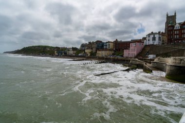 Cromer, UK- 18 Mayıs 2025: Seçkin renkli evleri ve kilise kulesi simgesi olan tarihi uçurum kenarı tatil beldesi. Hareketli dalgalar, kumlu kıyılar ve İngiliz cazibesiyle Idyllic sahil topluluğu