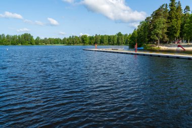 Kumlu kıyılar, ahşap yüzme limanları ve etrafını saran sık ormanlarla dolu sakin göl kıyısında bir tatil köyü. Manzaralı yaz fotoğrafı mükemmel bir tatil yeri ve boş zamanı yakalar.