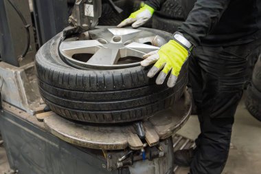 Mevsimsel Değiştirme Servisi Otomatik Makinesinde Profesyonel Mekanik Değiştirme Lastiği. Otomotiv Tamirhanesinde Yansıtıcı Eldiven Tekerlek Bağlama Ekipmanı Çalışıyor