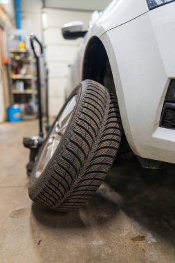 Otomobil Servisi Atölyesindeki Beyaz Araba Yön Tekerleği. Araç Bakım Güvenliği ve Otomotiv Hizmetleri Mevsimsel Lastik Değiştirme ve Değiştirme Konsepti