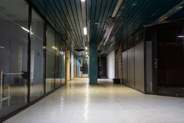 Terk edilmiş Tallinn Belediye Binası 'ndaki boş modern koridorda cam ofis bölümleri, mavi-yeşil tavan döşemeleri, temiz fayans döşemeleri, görünür havalandırma ve şık kurumsal mimari tarzlar sergileniyor.