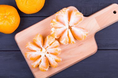 Bir kesme tahtası üzerinde soyulmuş mandalina
