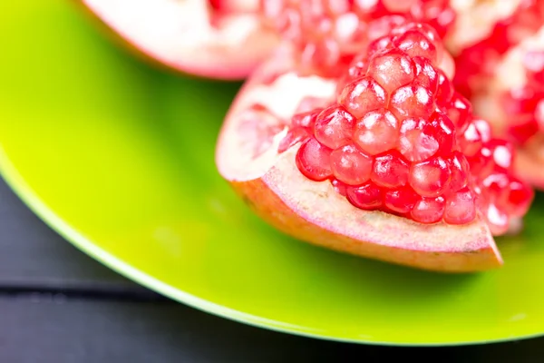 Pomegranate divided in a green plate — Stock Photo, Image