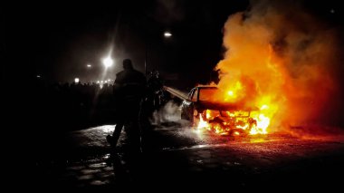İtfaiyeciler gece vakti yanan bir arabanın alevini söndürüyorlar, Veen, Hollanda