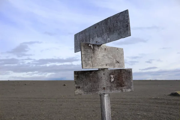 close-up of weathered wooden road sign in flat volcanic ash desert, Iceland