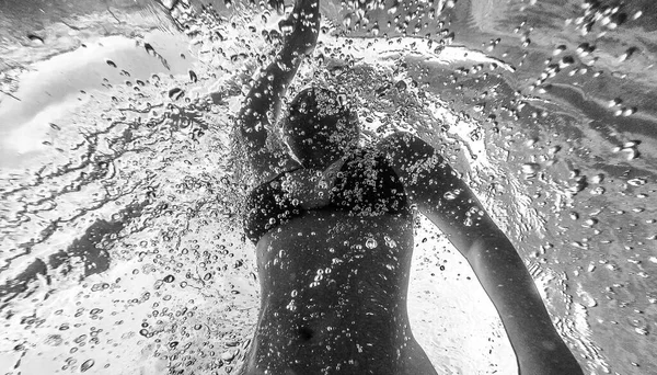 泳いでいるプールの泡の中を泳ぐ女性の黒と白の低角度水中写真 — ストック写真