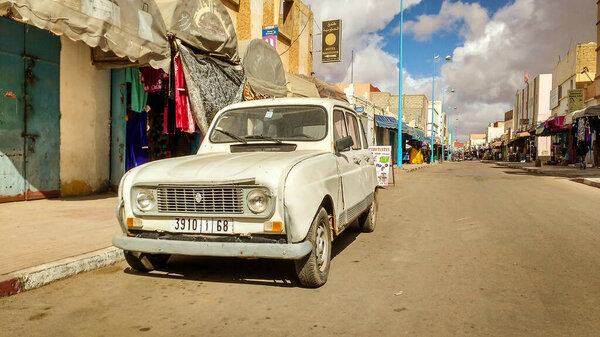 Tata, Morocco - January 21, 2017: Urban scene with vintage car Renault 4 on city dirt road with small shops and stores