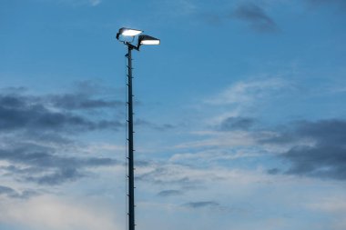Mavi gökyüzüne karşı stadyum projektör direği