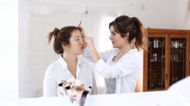 Güzellik salonundaki modelin yüzüne makyaj yaparken göz farı sürerken tanınmayan kadın vizyonu.