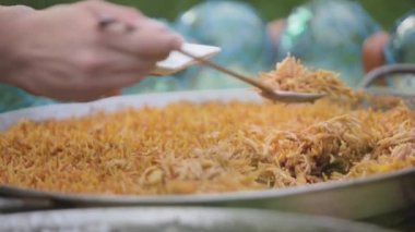 Büyük bir tavadan fideo paella servis eden tanınmamış biri.