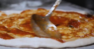 Pizza hazırlama sürecinin yavaş çekimleri domates sosu hamur üzerinde pişirme kaşığıyla yayılıyor.