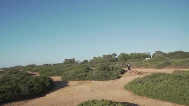 Siyah aktif giysili kadın huzurlu günbatımında yeşil deniz kenarında koşuyor.