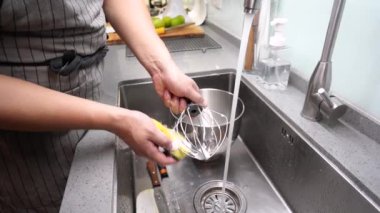 Ev fırını varken, kablo çırpıcısını lavaboda yıkayan tanınmayan birinin yan görüntüsü