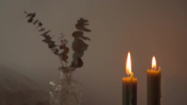 Yatak odasının içi, yakan mumların yanındaki eski kitap yığınına kuru bitkiler konmuş, ahşap el yapımı komodinlerle dolu.
