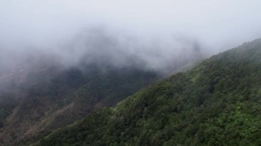 Picturesque aerial view of winding mountain road under clouds on foggy and windy day in highlands