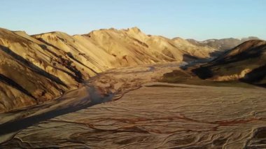 Kuru otlarla kaplı engin vadinin ve İzlanda 'da tenha tepelerin yakınındaki dar kıvrımlı nehirlerin görüntüsünü oluşturuyorum.