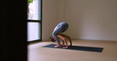 Yoga antrenmanında Firefly Asana performansı sergilerken kolları üzerinde dengede duran taytlı güçlü genç bayan sporcu.