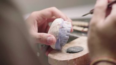 Laboratuvarda takma diş üretirken alçı çene ve seramik dişleri şekillendiren tanınamayan erkek üstadın yakınlaştırılması