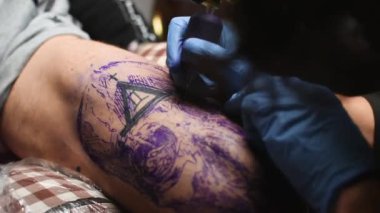 Dövmeci, müşteriyle kuaförde çalışıyor.