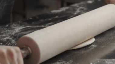 Mutfakta çalışırken hamuru oklavayla geren isimsiz bir aşçı.