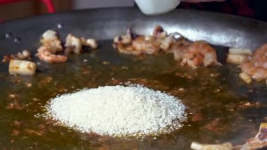 Anonim şef tavaya pilav ekliyor ve mutfakta kızartma yapıyor.