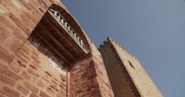 Tepsinin altından, güneşli bir günde mavi bulutsuz gökyüzünün arka planında taş cepheli kuleleri olan antik kalenin sağ görüşü.