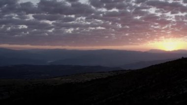 Aerial view of picturesque landscape of mountainous valley against colorful sky with sun setting over horizon