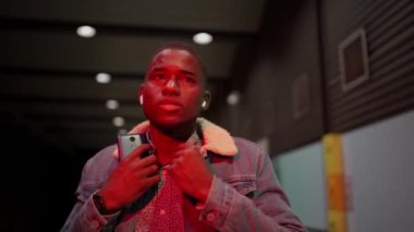 İstasyonda yürüyen ve müzik dinleyen siyah bir adam.