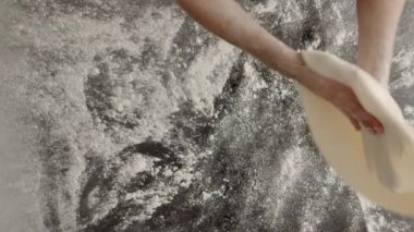 Lokanta mutfağında pizza tabanı gererken unlu hamur atan isimsiz bir adamın en iyi görüntüsü.