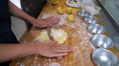 Evinde ahşap tezgahta çalışan önlüklü, hamurlu, tanınmayan biri.