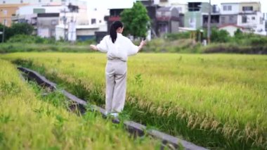 Yeşil alanda selfie çubuğuyla yürüyen ve akıllı telefondan fotoğraf çeken etnik bir kadın.