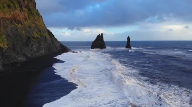 Fırtınalı İzlanda 'da fırtınalı bir günde dalgalı deniz dalgalarının dalgalı kayalıkların yanında yuvarlanışını ve sıçrayışını gösteren resimli drone görüntüsü.