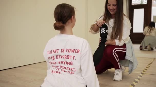 Χαμογελώντας Εκπαιδεύτρια Αθλητικά Ρούχα Βοηθώντας Χαρούμενο Κορίτσι Τεντωμένα Πόδια Ενώ — Αρχείο Βίντεο