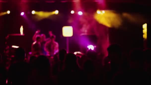ネオンライトステージで照らされた音楽を演奏するディスクジョッキーと人々が踊る現代のクラブでの夜のパーティー — ストック動画