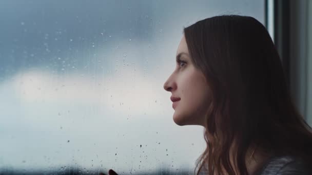 Vista Lateral Fêmea Tranquila Perto Janela Observando Chuva Através Vidro — Vídeo de Stock