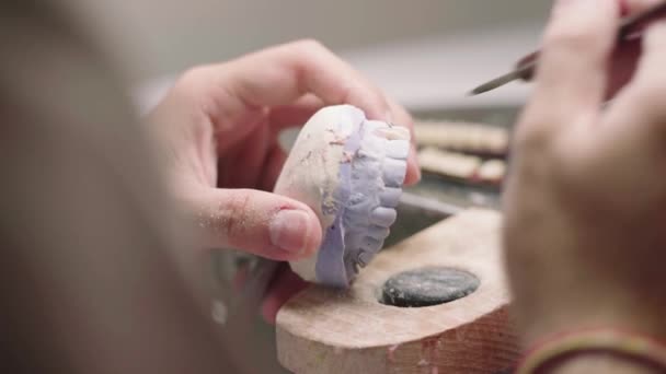 石膏の顎で作業し 実験室で入れ歯を製造しながらセラミック歯を形成する認識できない男性のマスターの閉鎖 — ストック動画
