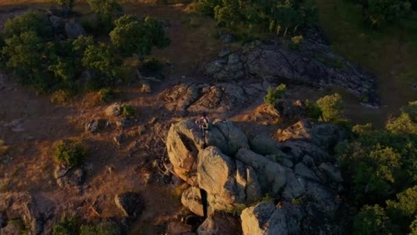 自然景観を背景にブリタゴ ロゾヤの石に座って夏休みを楽しみながら手を振っている観光客のカップルのドローンビュー — ストック動画