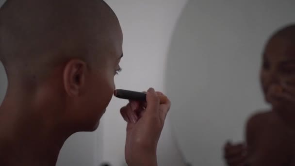 Konsentrert Afroamerikansk Kvinne Med Skallet Hårklipp Ser Seg Speilet Bruker – stockvideo