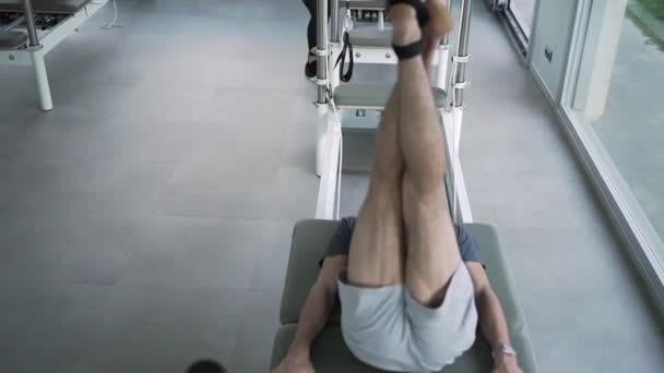 Homem Activewear Deitado Pilates Reformador Com Tiras Com Perna Levantada — Vídeo de Stock