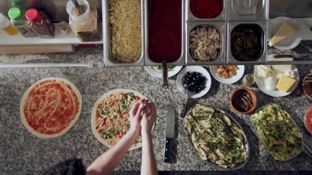 피자를 준비하는 대리석 카운터에 야채와 부엌에 재료와 식기들로 피자를 준비하는 — 비디오