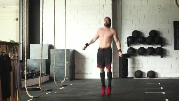 筋肉の無慈悲な男性アスリートは スローモーションでジムでの心臓トレーニング中にロープをジャンプ — ストック動画