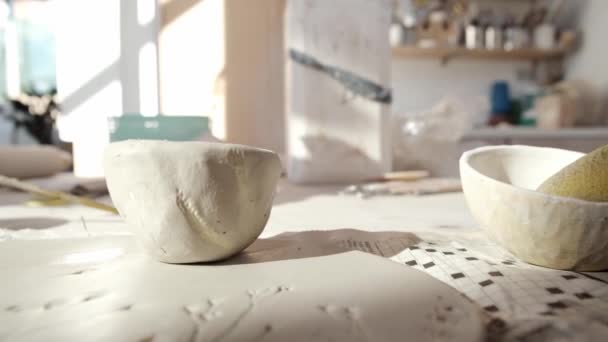 陶器の工房でテーブルの上に汚れたブラシで粘土で作られた白いボウル — ストック動画