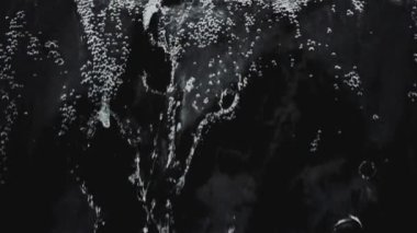 Şeffaf suyun aktığı ve siyah arkaplana karşı yavaş çekimde sıçrayan soyut arkaplan