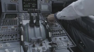 Anonim erkek kaptan ve pilotun arka planda modern uçağın kokpitinde oturup kalkışa hazırlanırken ekipmanları kontrol etmesi.