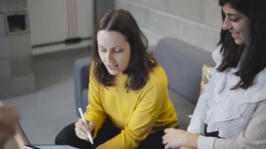 Bir grup yaratıcı milenyum tasarımcısı kahve içip grafik tabletindeki yeni proje için tasarım tartışırken aynı zamanda modern çatı katında iş birliği yapıyorlar.
