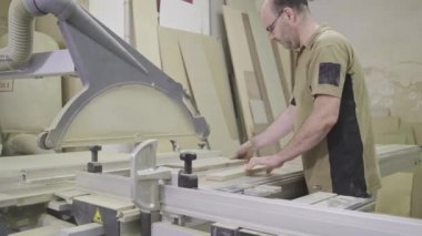 Dikkatli marangoz atölyede budama makinesi kullanarak odun kesiyor.